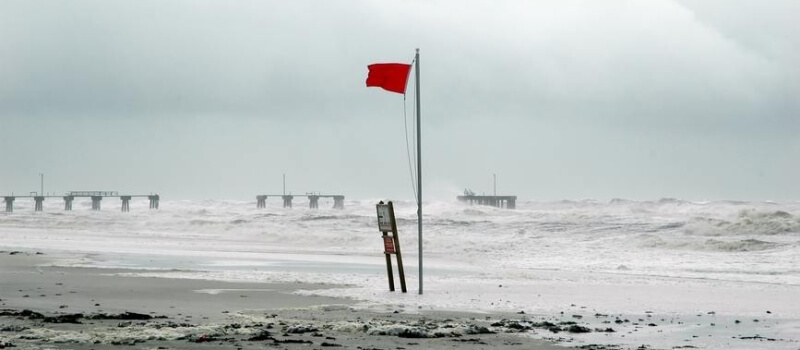red flag waving on stormy beach