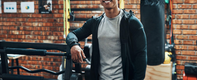 Cropped portrait of a handsome young male fitness instructor smiling while standing in a gym