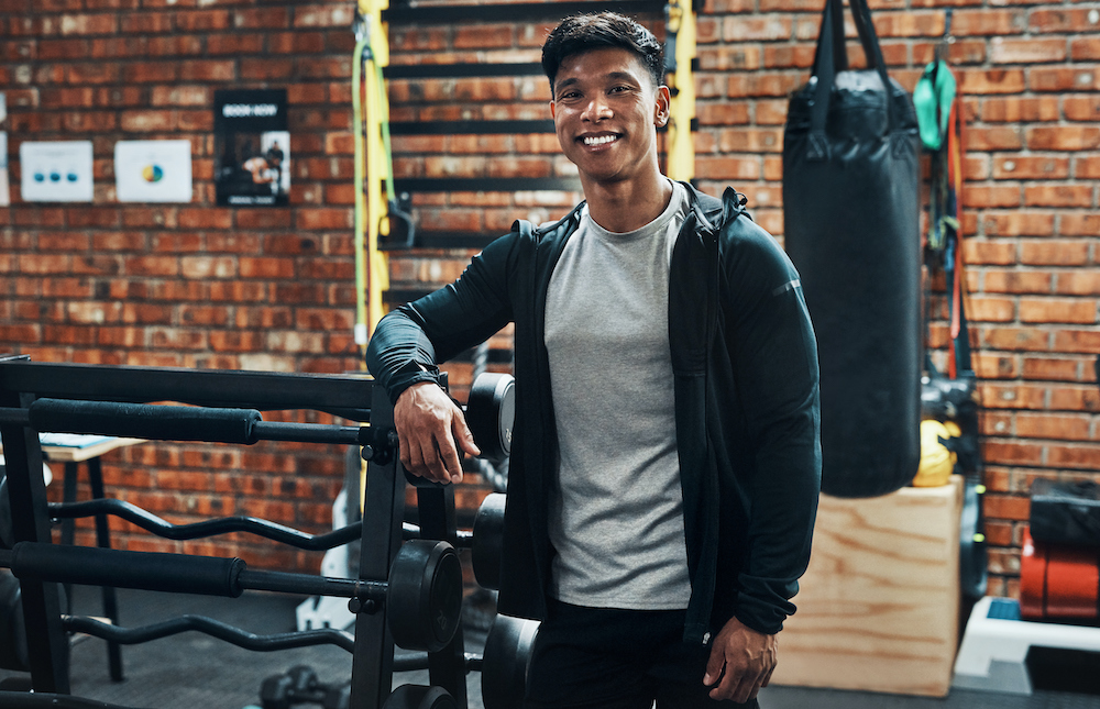 Cropped portrait of a handsome young male fitness instructor smiling while standing in a gym