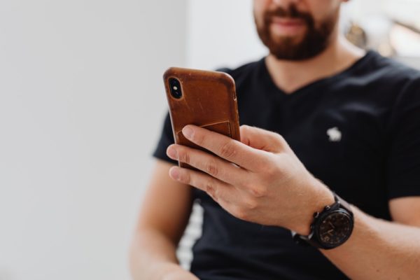 man touching smartphone with thumb