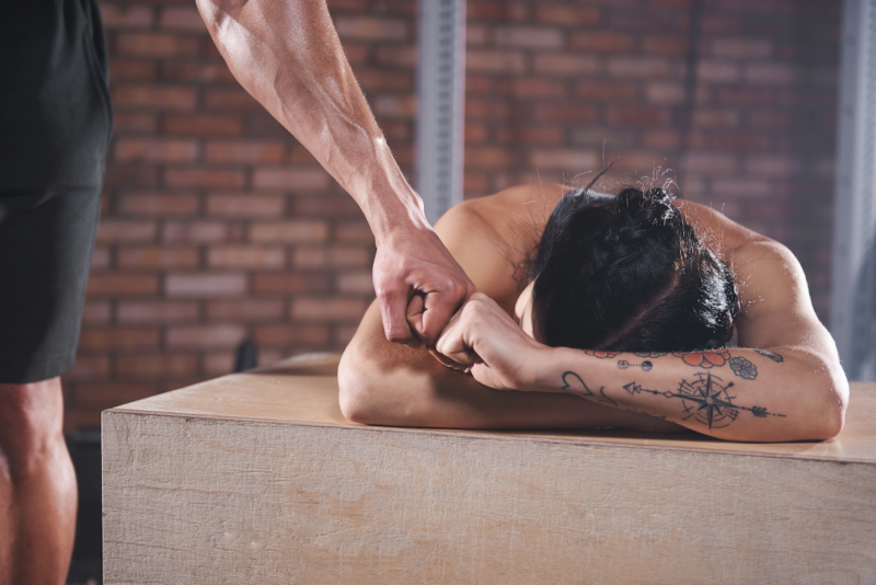 2 CrossFit athletes giving fist bumps on a wood plyo box