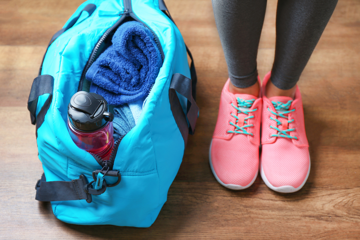 Gym bag with water bottle and towel and a pair of pink sneakers