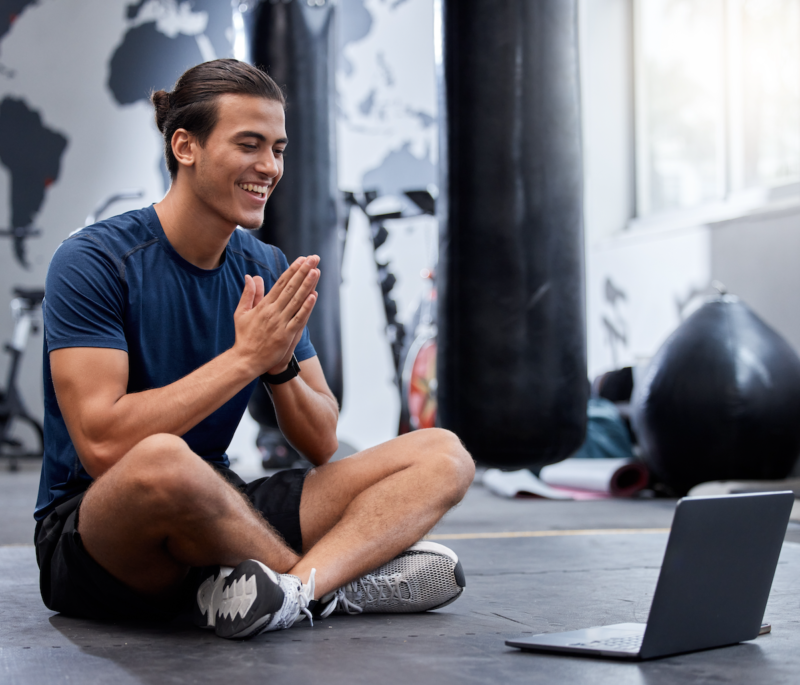 Man sitting smiling at laptop in gym