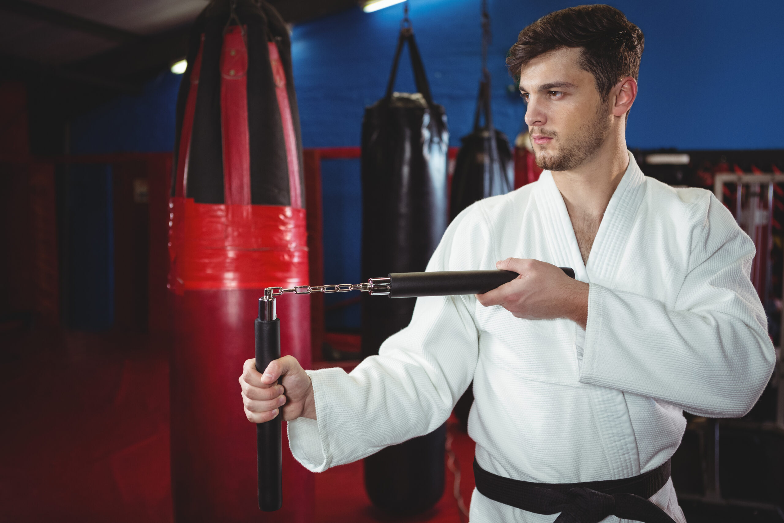 Karate player practicing with nunchaku in fitness studio A Martial Arts Student Practicing at a Gymnasium