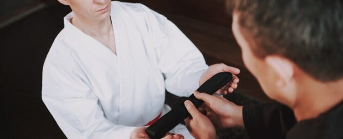 Martial Arts Student Receiving a Black Belt During a Promotion Ceremony