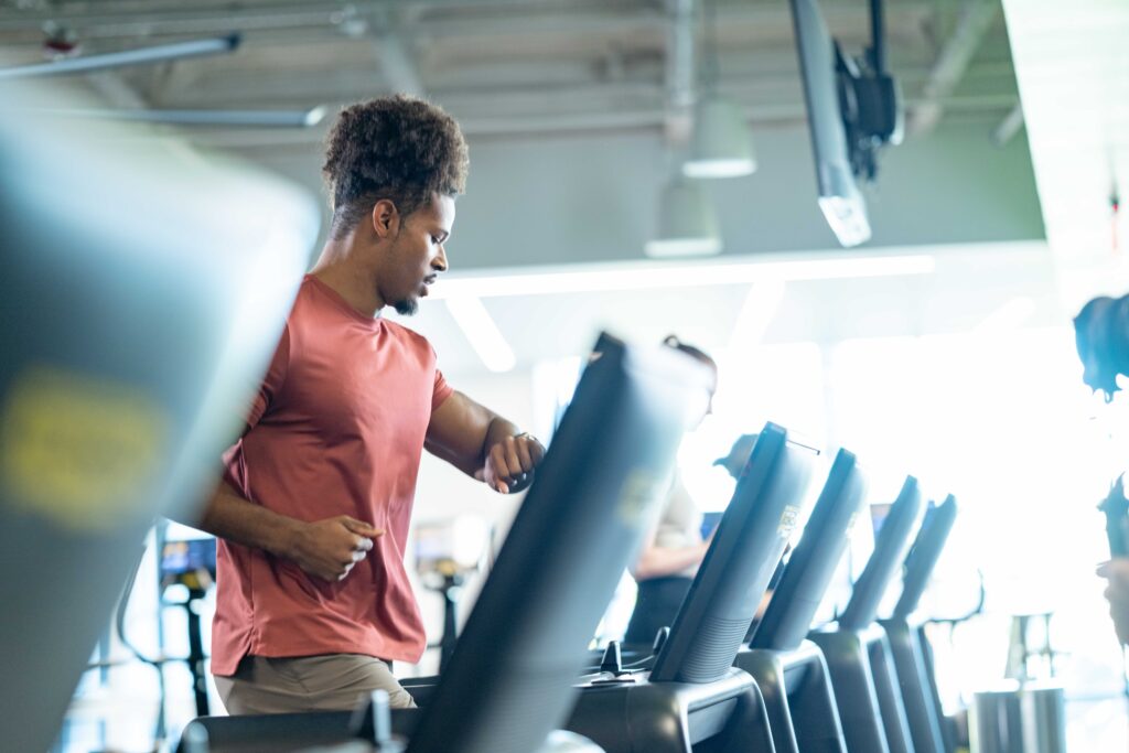 A boutique gym owner using a tablet to check gym membership software while clients train in the background