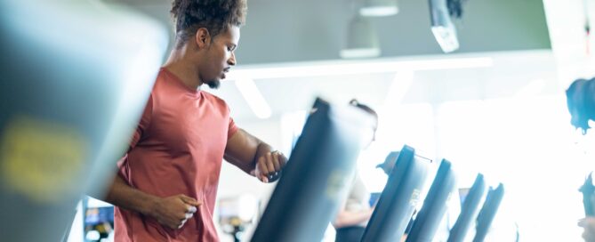 A boutique gym owner using a tablet to check gym membership software while clients train in the background