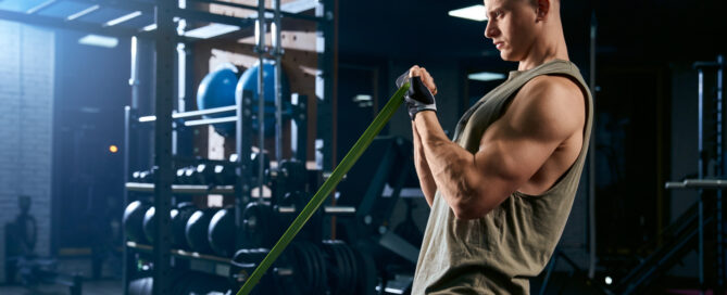 Bodybuilder training arm with a resistance band in a gym