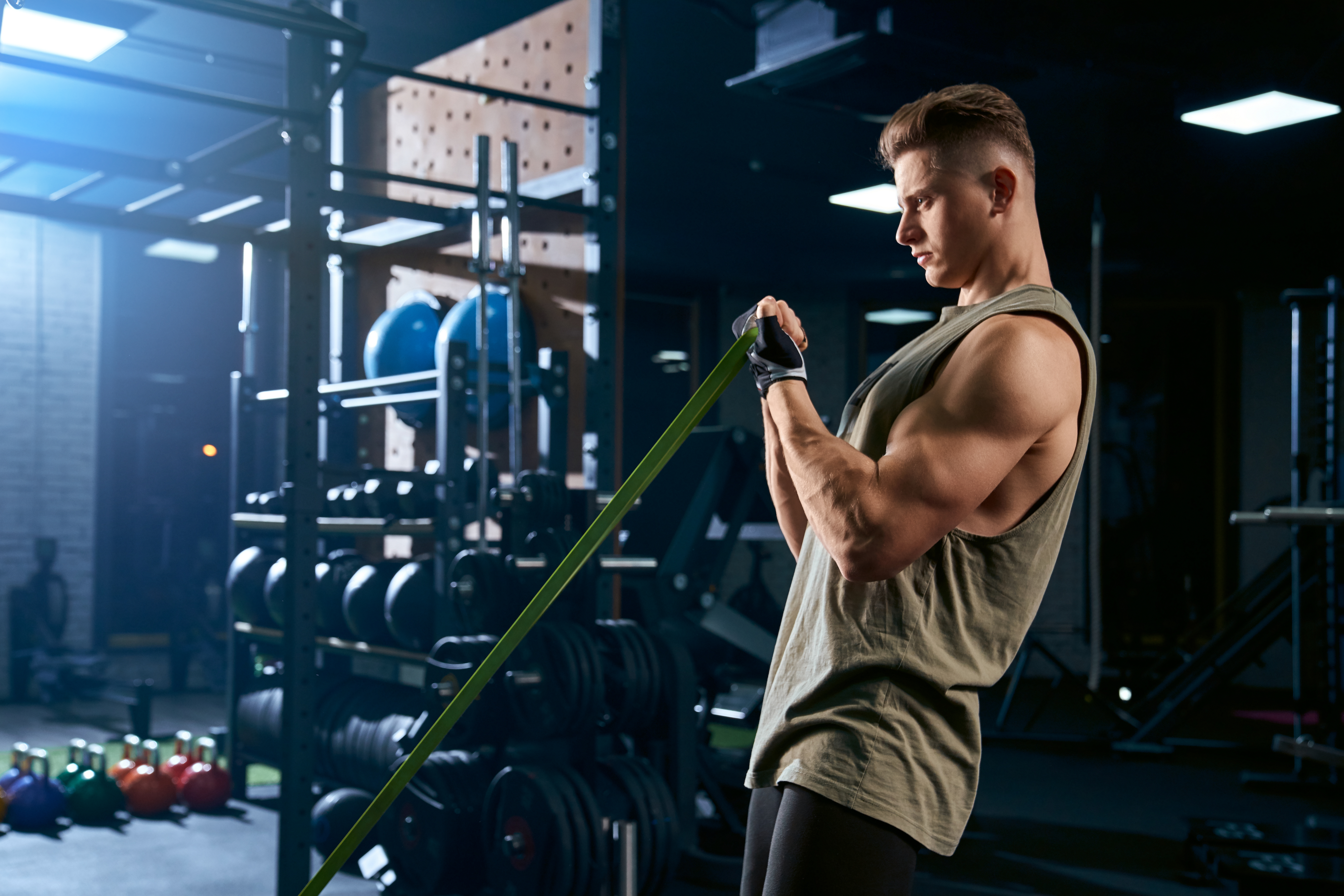 Bodybuilder training arm with resistance band. Bodybuilder training arm with a resistance band in a gym