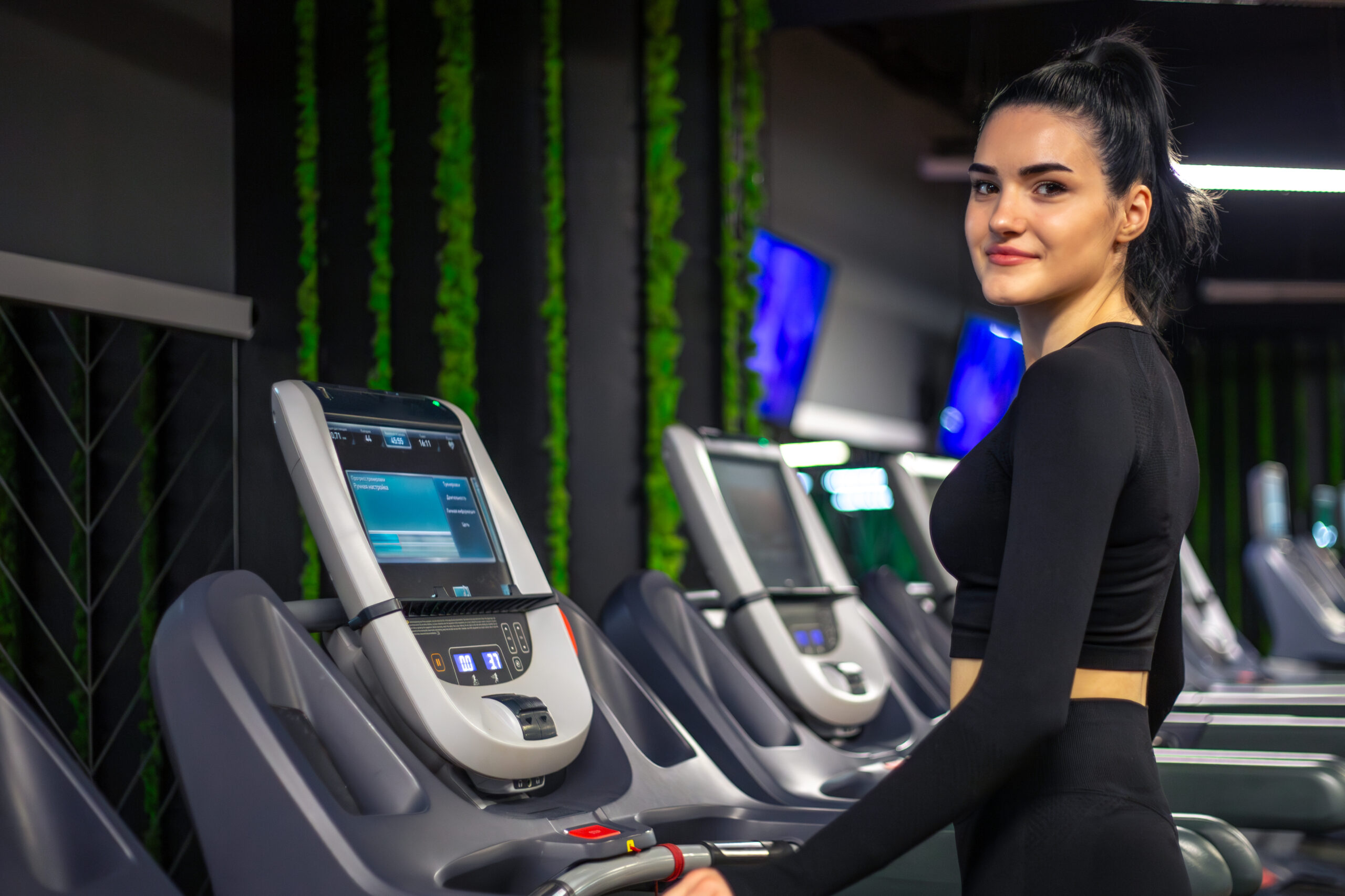 Woman posing beside advanced equipment in a gym