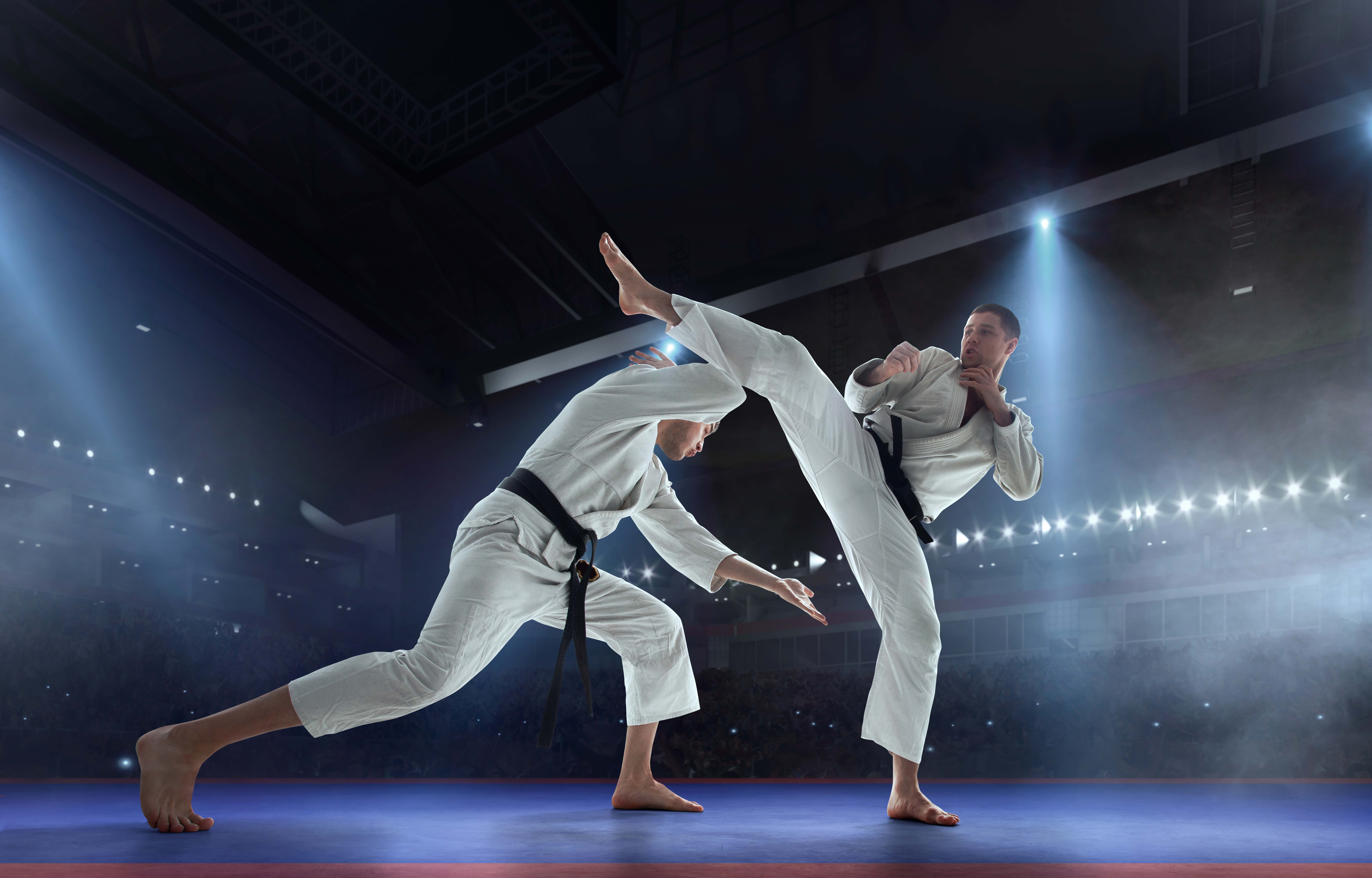 Karate fighters sparring with a high kick in a martial arts competition