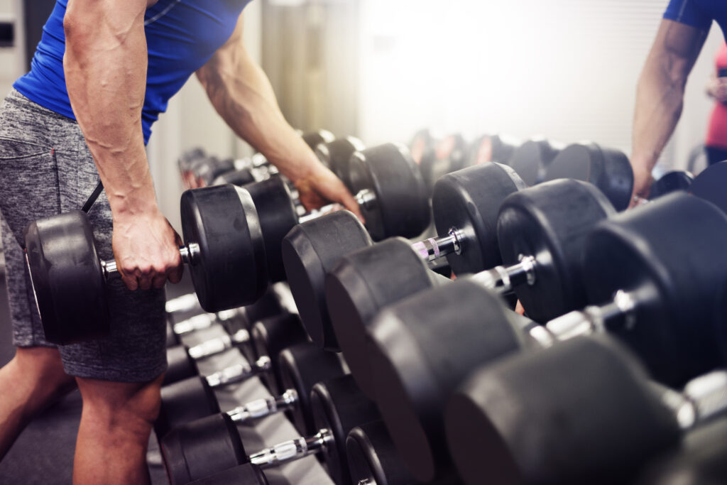 Man selecting dumbbells from a rack for weight training at the gym