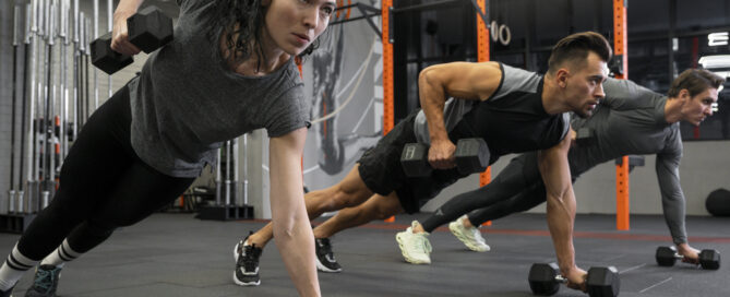 People working out in a fitness studio together with dumbbells