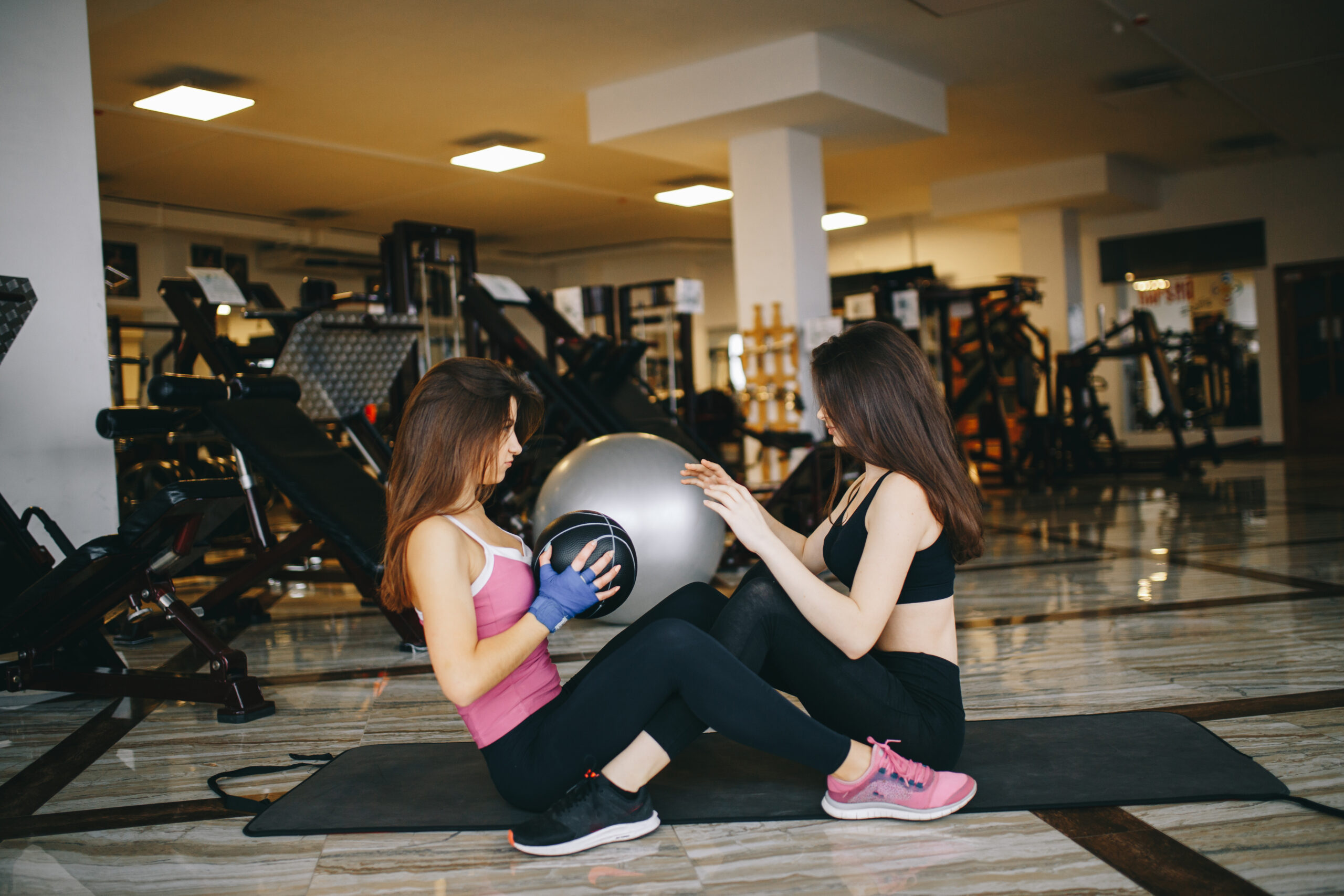 Two athletic girls in the gym Two women doing a partner workout with a medicine ball in a gym