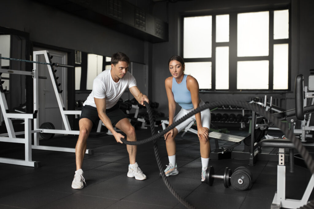 Man and woman training together with battle ropes in a fitness studio
