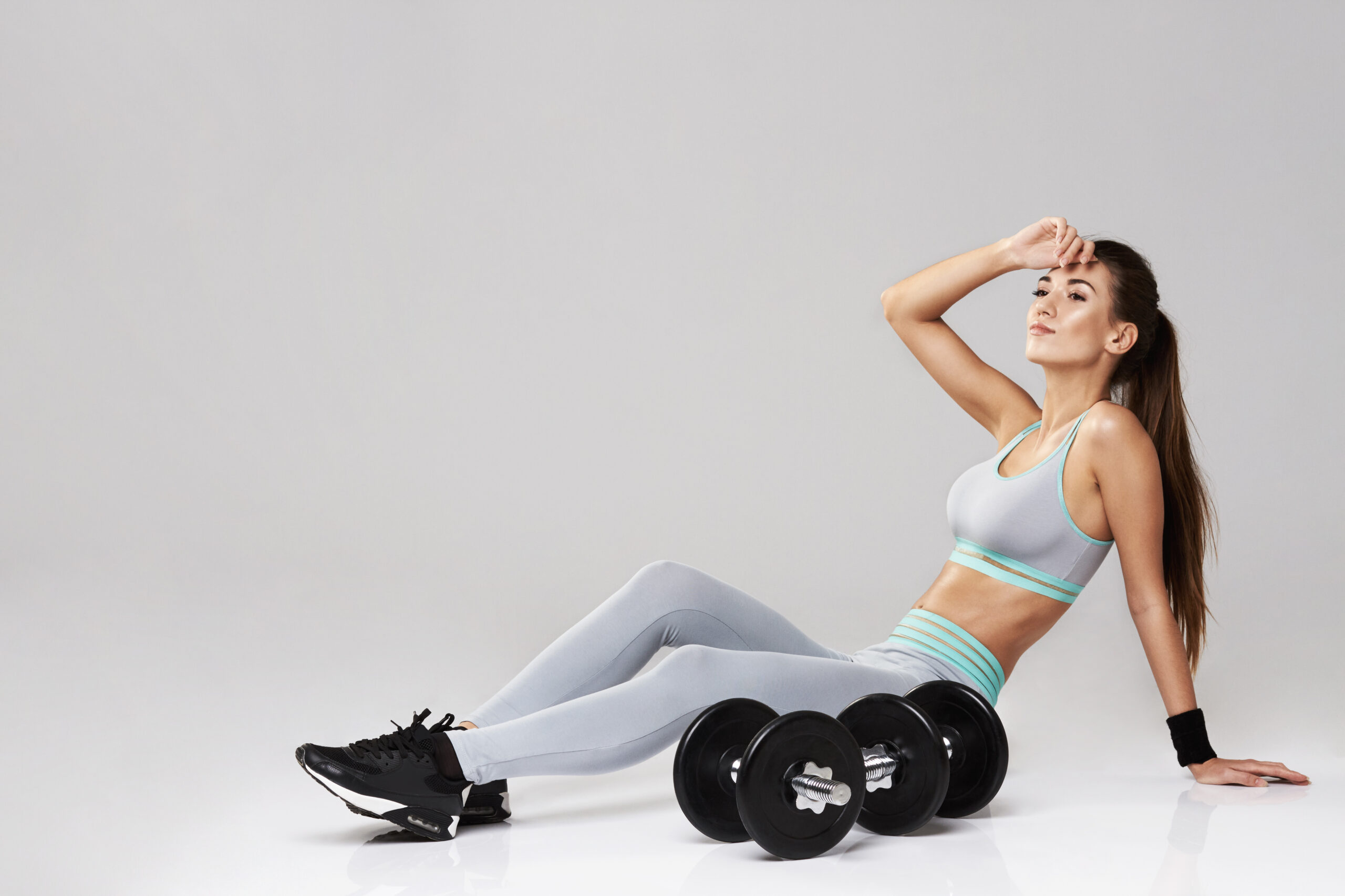 Woman relaxing post-workout with dumbbells nearby