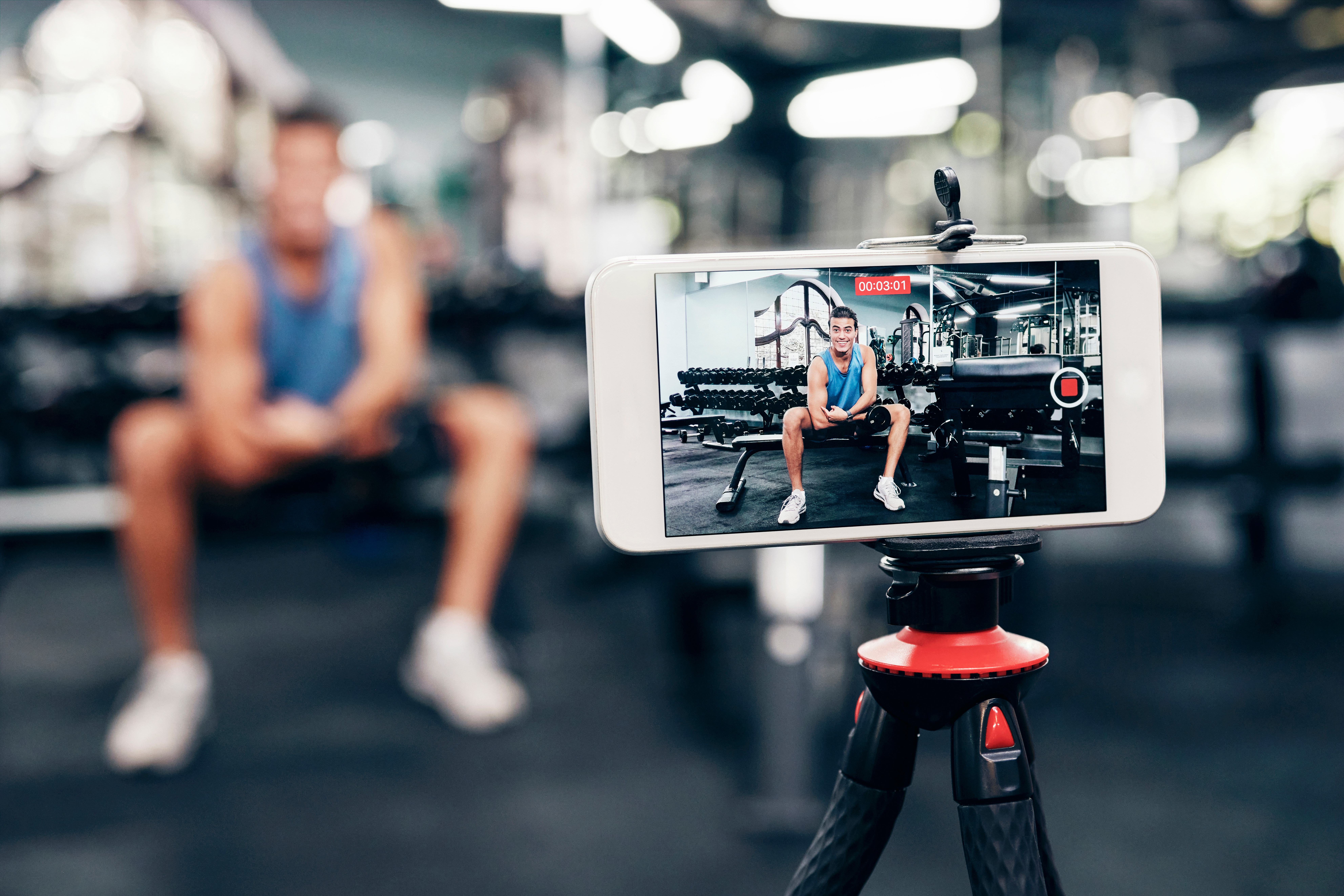 A social media and fitness influencer with phone live streaming workout for interactive multimedia broadcast and trying to market himself authentically.