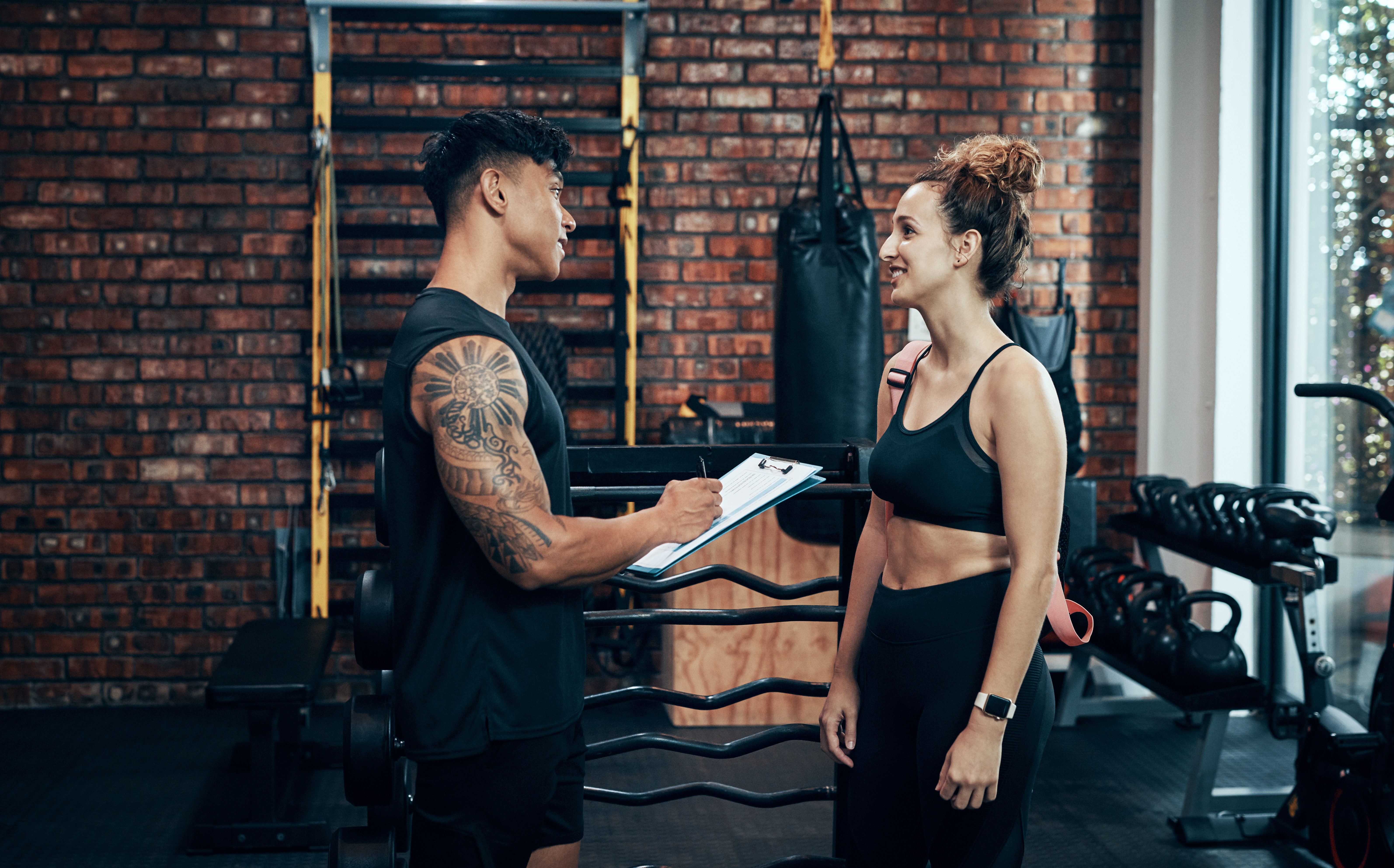 Signup with us, you wont regret it. Shot of a sporty young woman talking to a fitness trainer at the gym. A coach giving gym nutrition coaching to one of the gym members post a workout session.