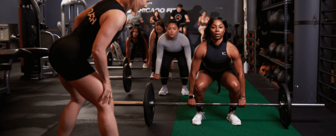 CrossFit coach leading a beginner on-ramp class inside a CrossFit gym