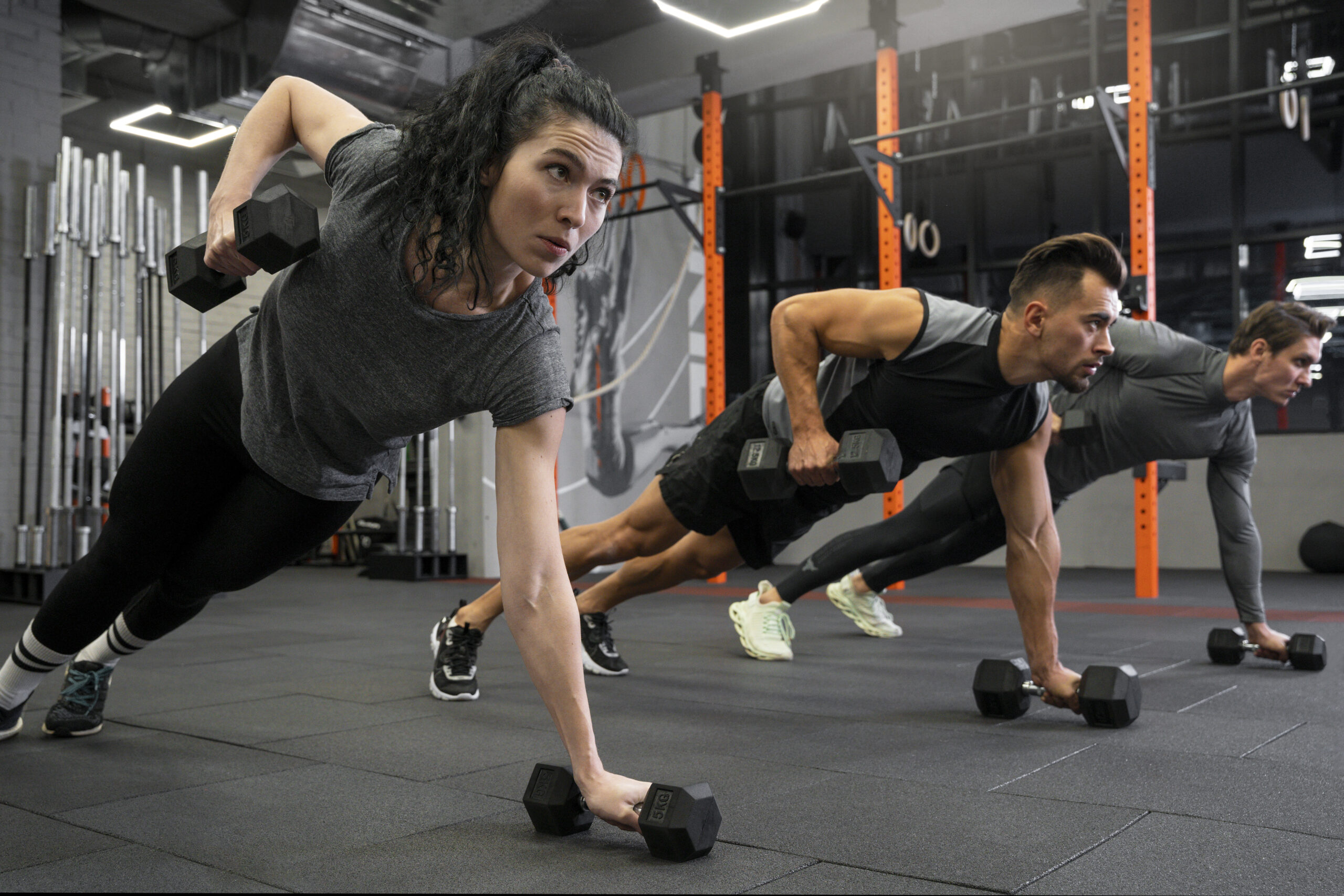 Members working out in a group inside a gym with dumbbells.