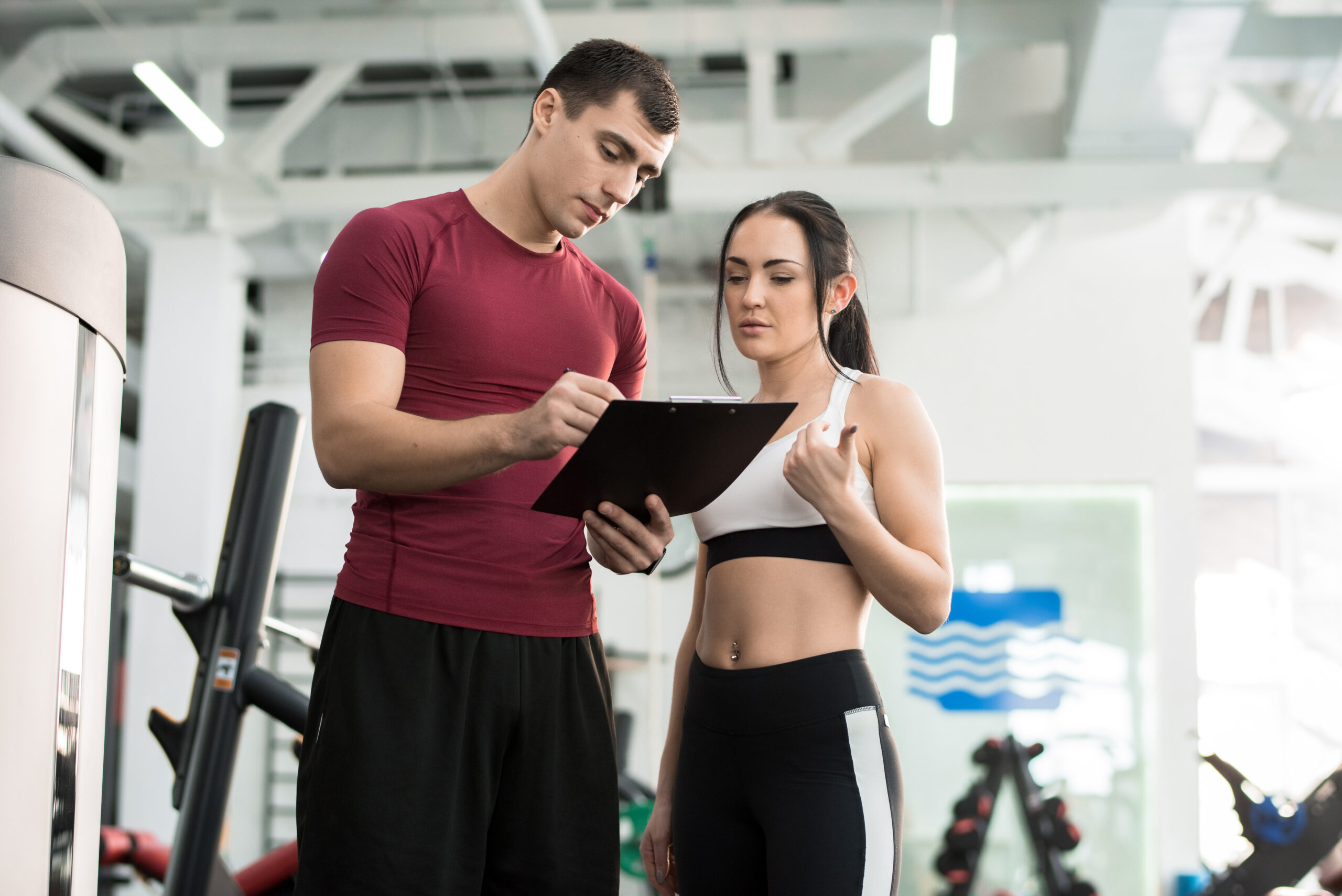 A shot of young trainer taking feedback and conducting monthly reviews from a female gym member.