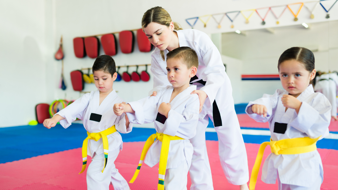 A martial arts instructor teaching and training kids in a dojo.