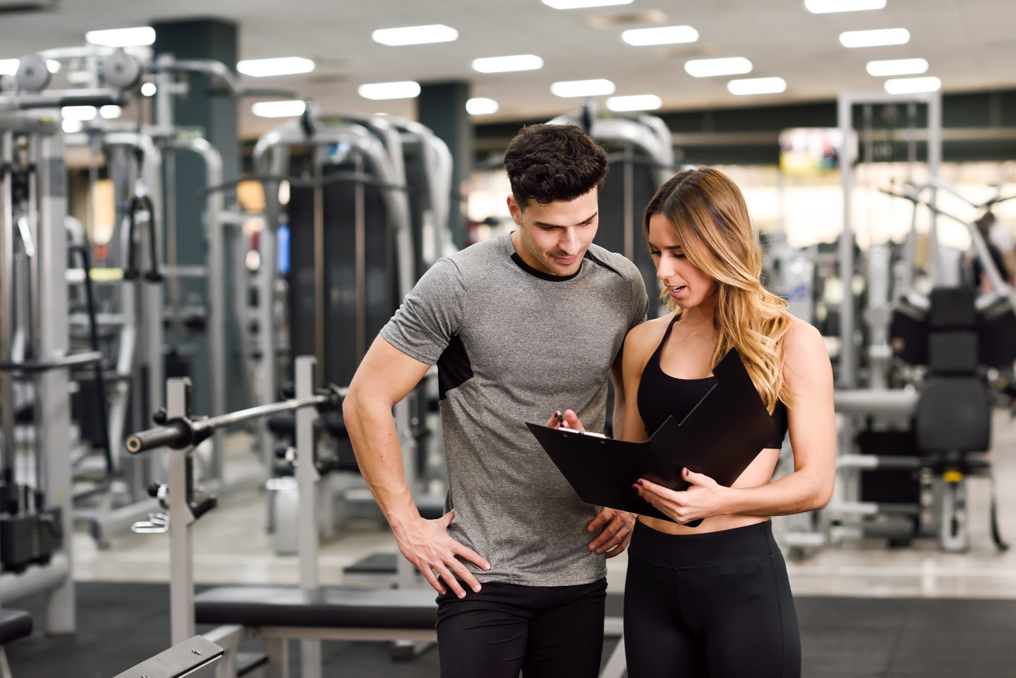 Tablet with gym membership tracking software in use, gym members working out in background