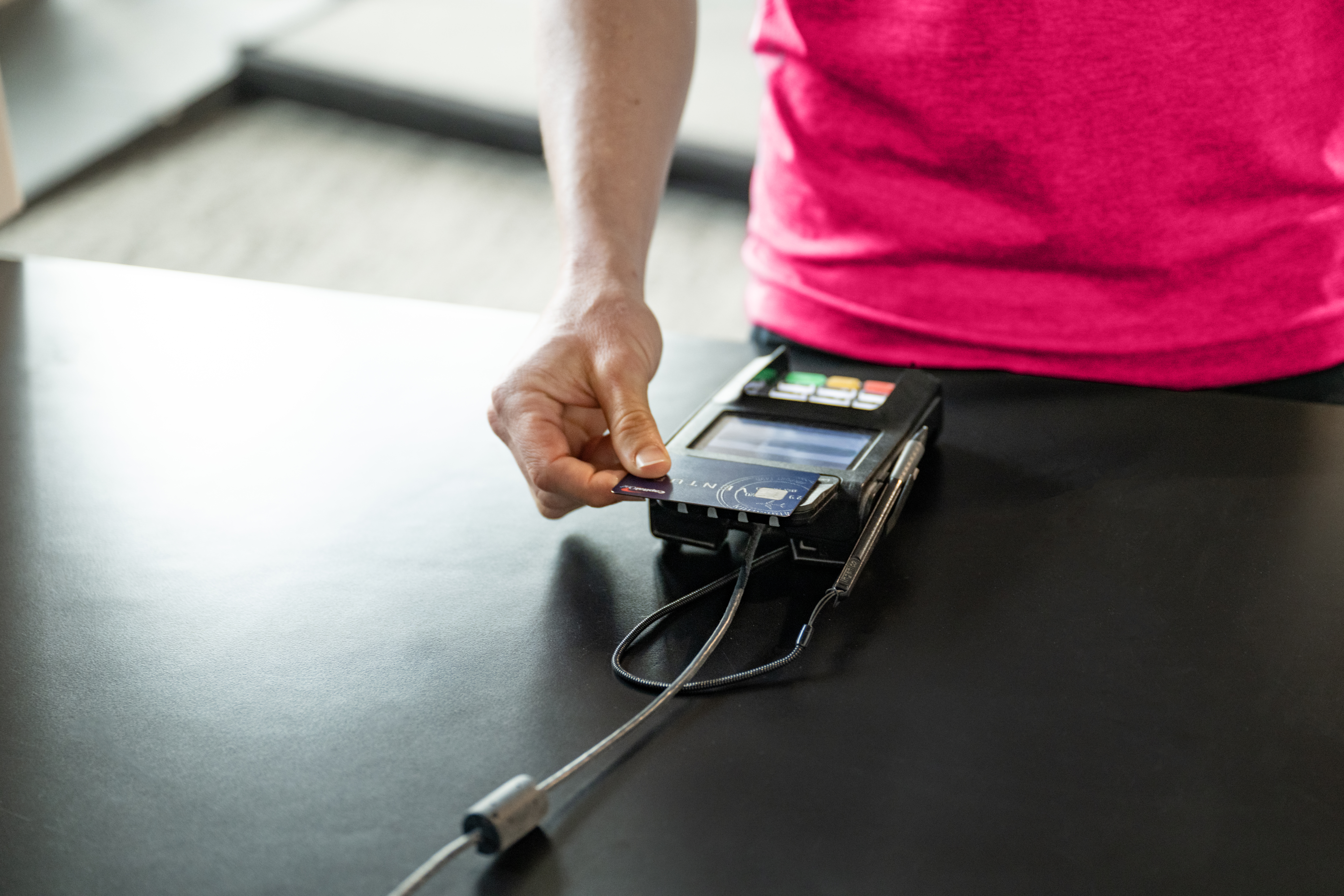 DAXKO-199-vitality Customer making a secure card payment at a gym checkout counter using a credit card terminal.