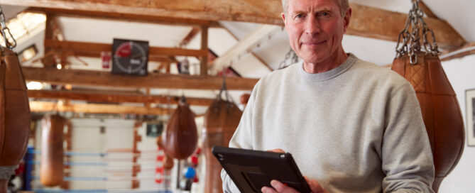 Kickboxing gym owner using studio management software to review class schedules, student attendance, and business performance.