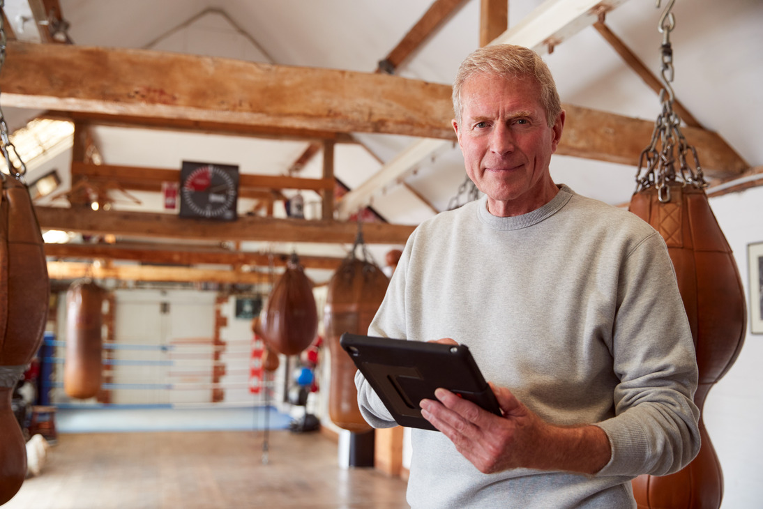 Kickboxing gym owner using studio management software to review class schedules, student attendance, and business performance.